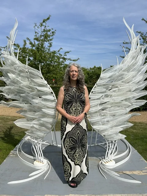 Lynn standing in front of white wing sculptures