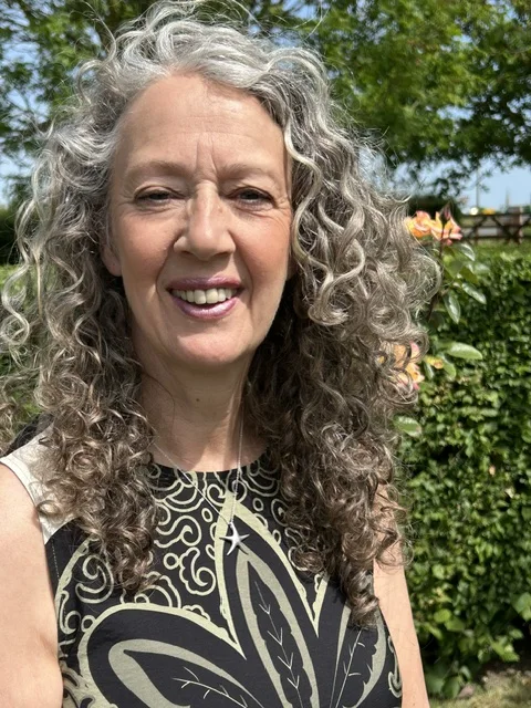 Lynn McGhee smiling in a garden portrait