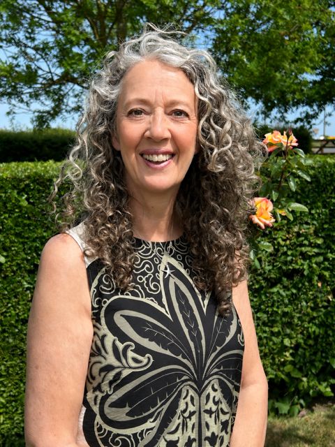 Lynn McGhee smiling in a garden portrait