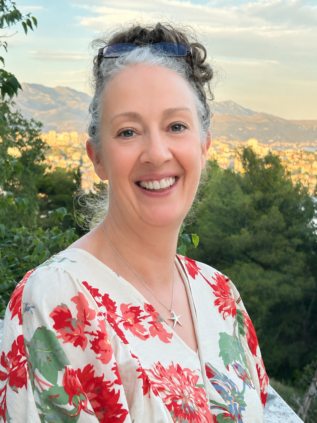 Lynn smiling outdoors in a floral blouse
