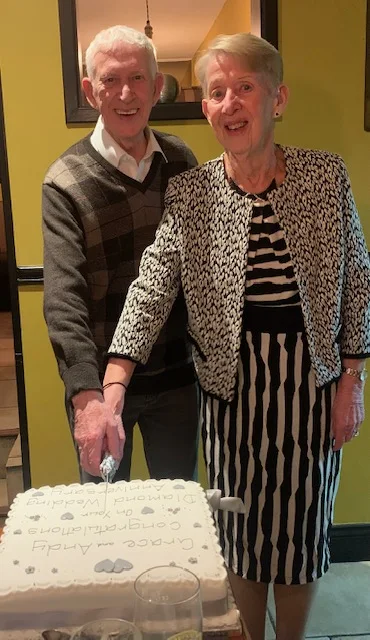 A couple celebrating together beside a cake